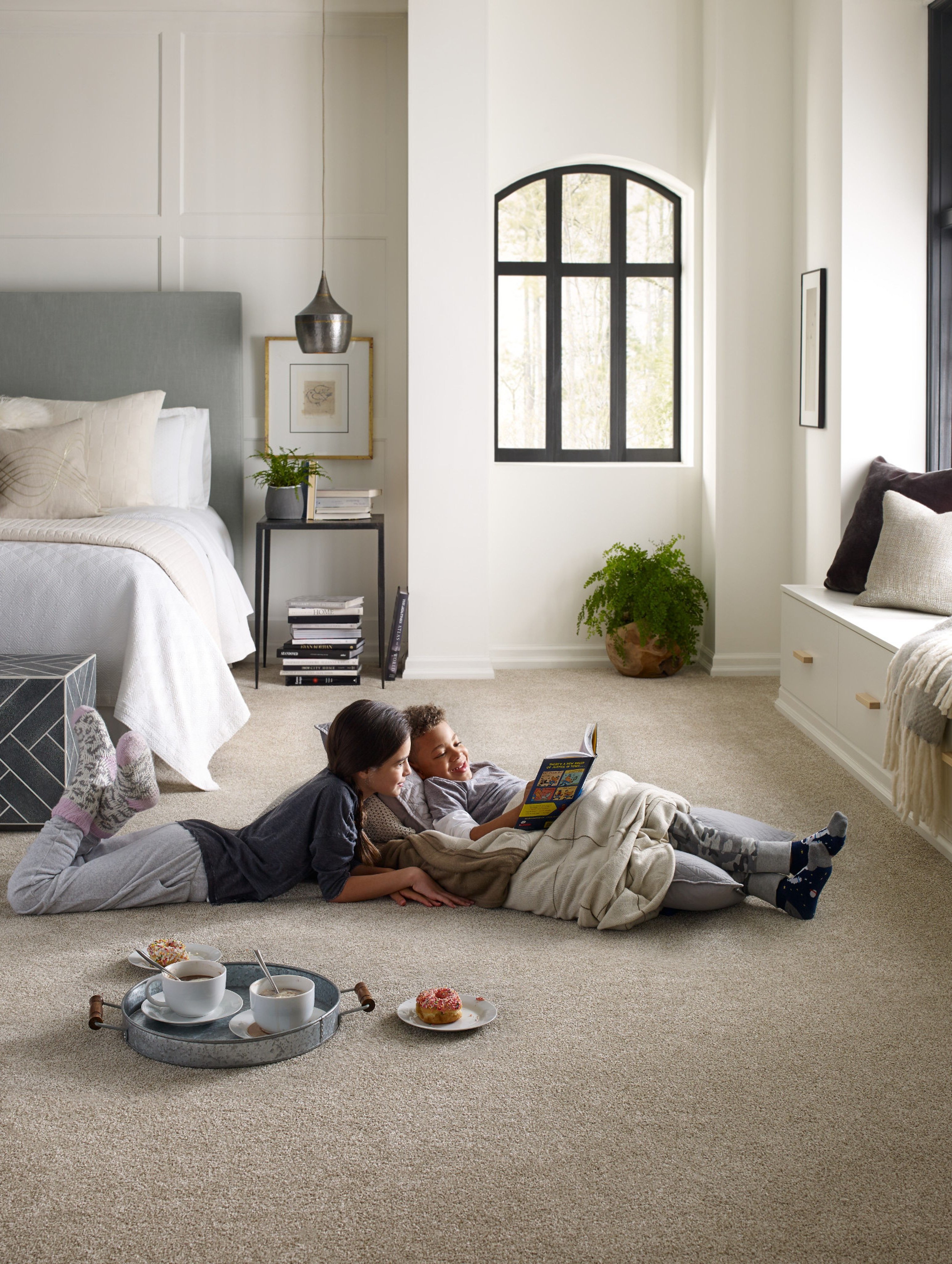 two kids laying in bedroom reading a book