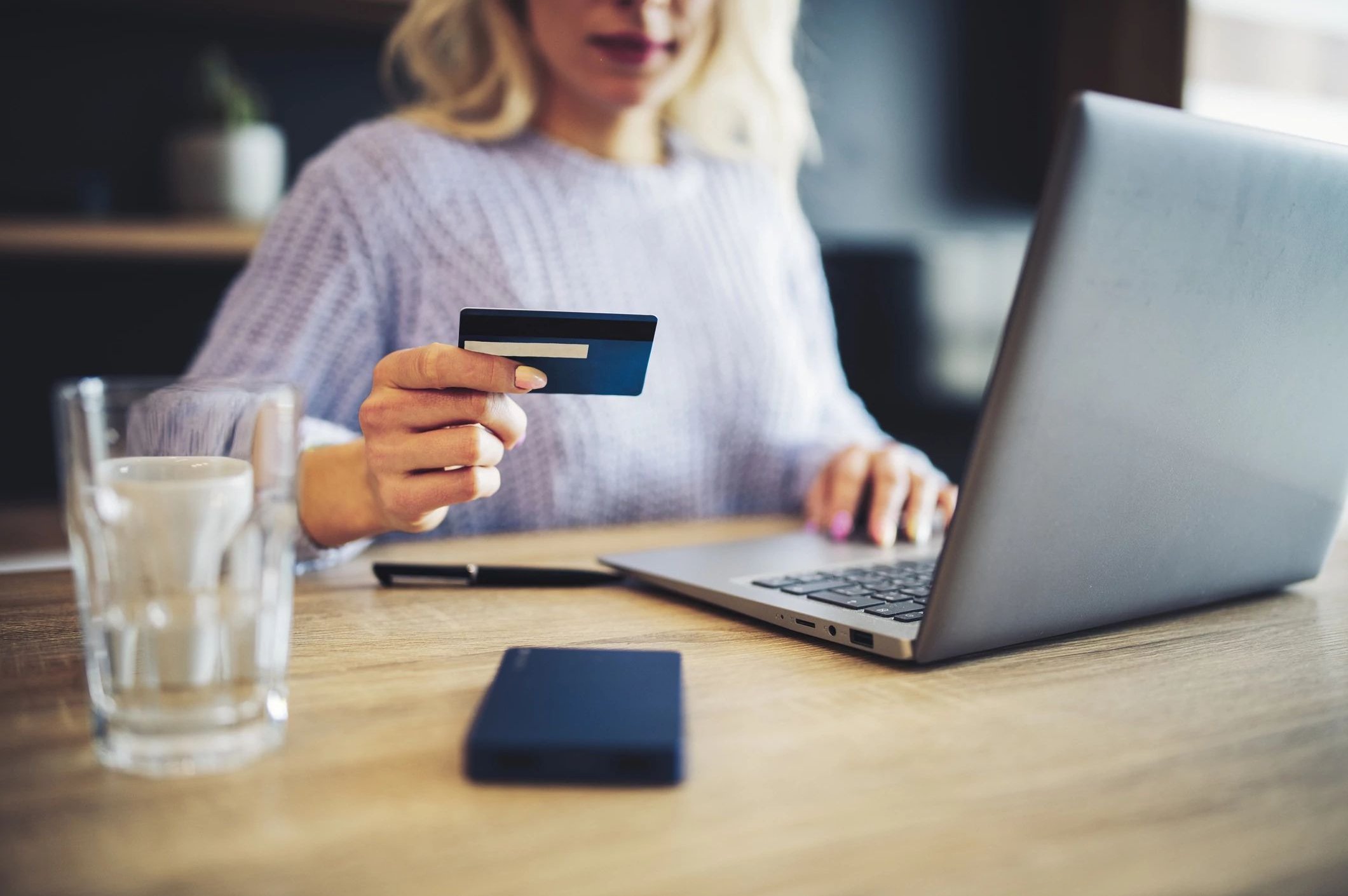 woman holding credit card while using laptop